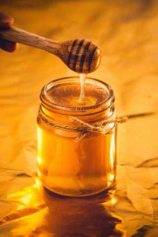 jar of honey and spoon with honey dripping